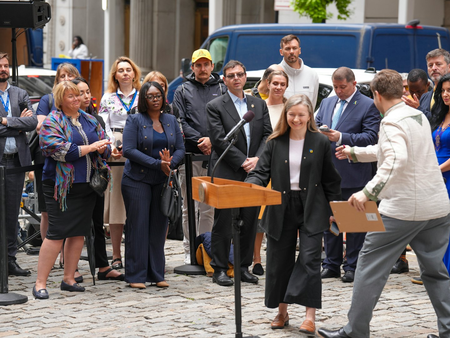 A woman speaks at a podium while receiving a clipboard.