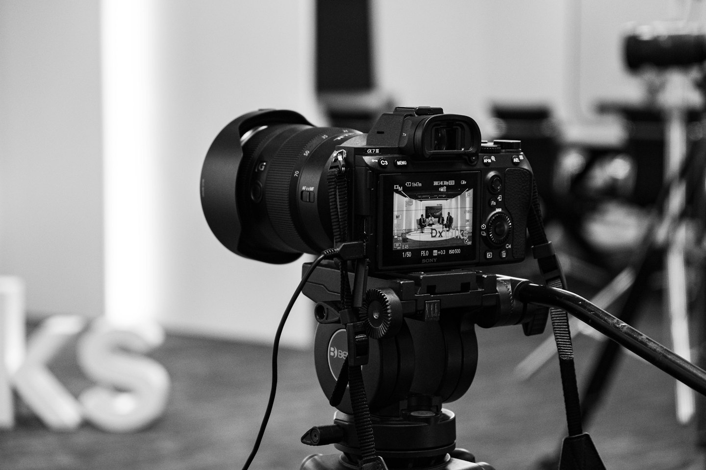 A camera on a tripod recording a corporate panel discussion.
