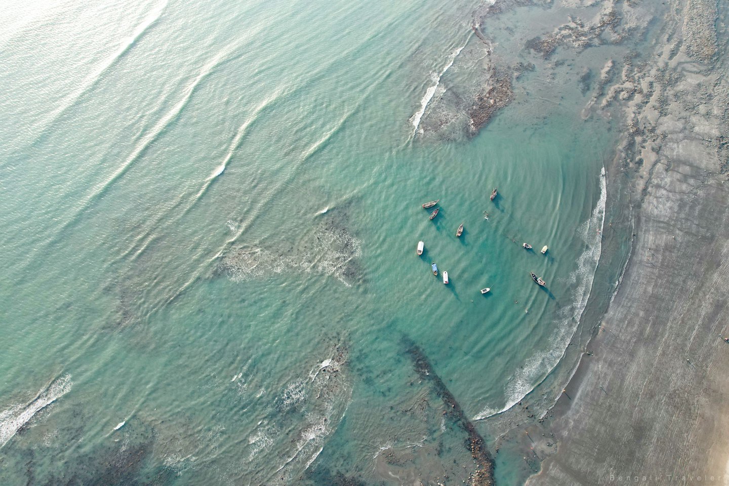 Small fishing boats anchored in shallow coastal waters.